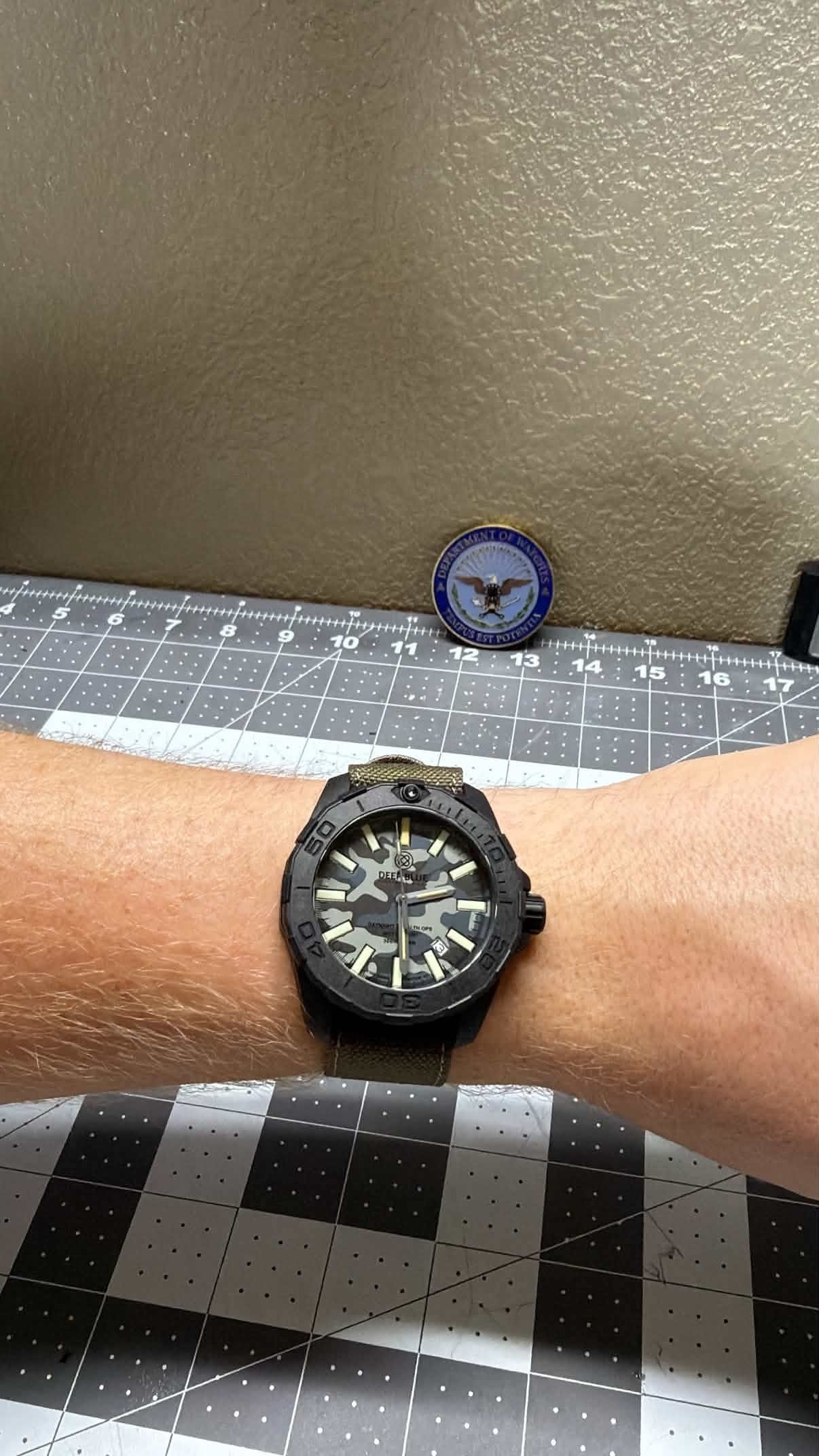 The Deep Blue DayNight Stealth Ops on the winner's wrist, with a Department of Watches challenge coin